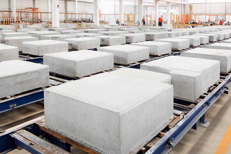 Mehrere fertige Betonbauteile auf Schalungstischen in der Produktionshalle